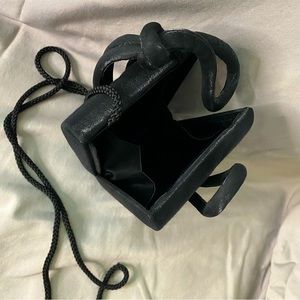 Dainty black evening clutch. Knotted top with rope strap.